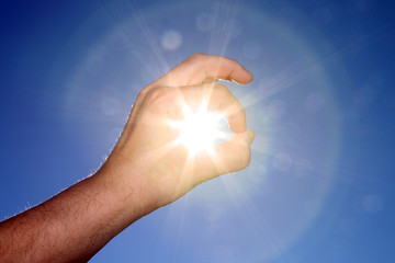 Hand catching the sun on blue sky