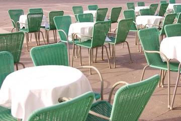 Terrace with green chairs and round tables