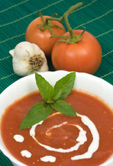 tomato soup decorated with sour cream and basil leafs