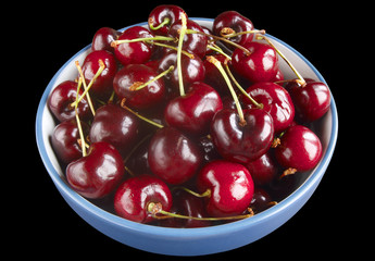 Cherries in a bowl isolated on a black background.