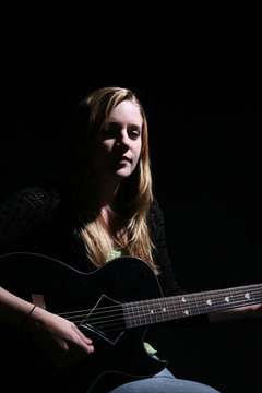 woman playing guitar with dramatic lighting