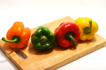 four colors bell peppers on wooden plate