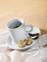 cup of espresso with brown sugar on a table with tablecloth