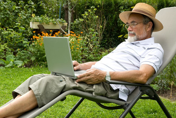 senior  in garden at leisure with laptop computer
