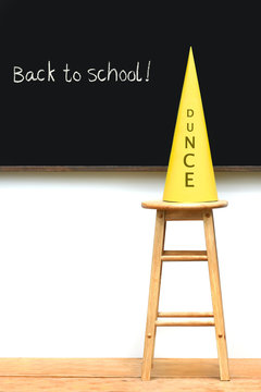 Yellow dunce hat on stool with chalkboard