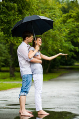 Portrait of man hugging happy woman under umbrella