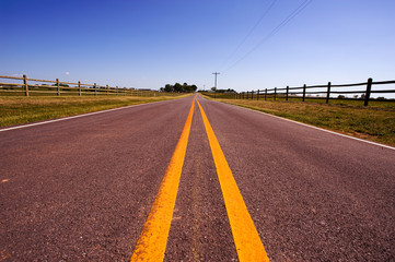 A long road bordered by farm fences