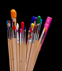 A group of multi-color painbrushes on a black background