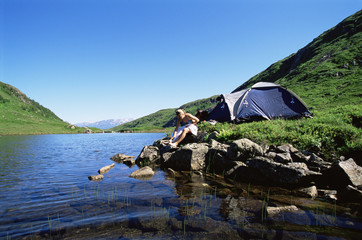 Fototapeta na wymiar Young woman washing in lake next to camp