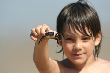 garçon qui tient un crabe entre ses doigts