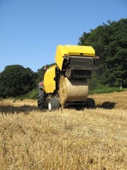 Baler discharging a round bale of wheat during harvesting