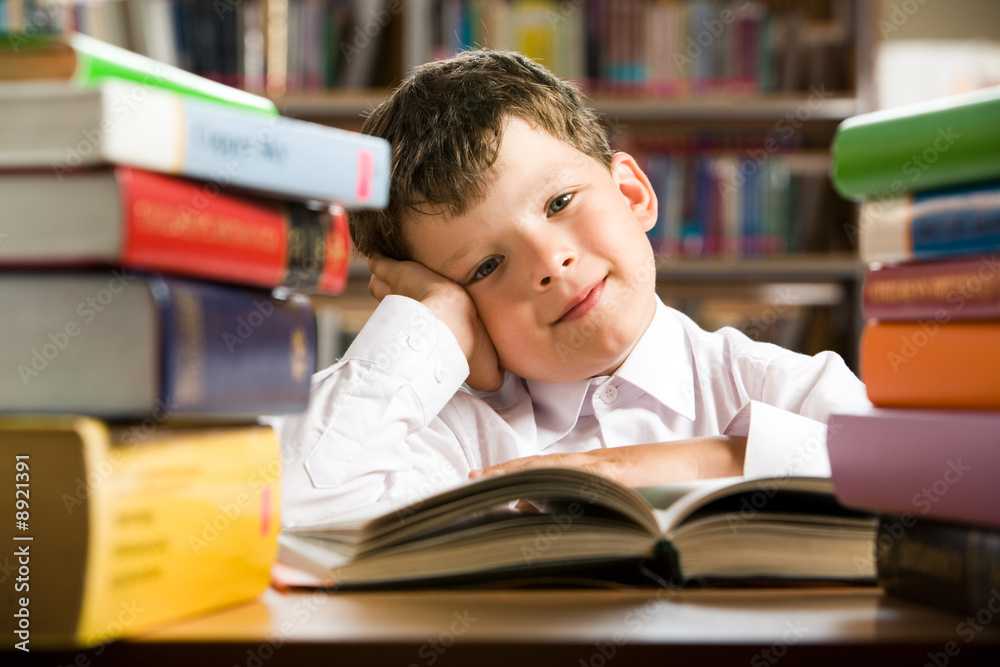 Sticker portrait of cheerful lad sitting in library before book