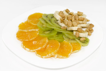 slices of an orange, a banana and kiwi, from above a peanut