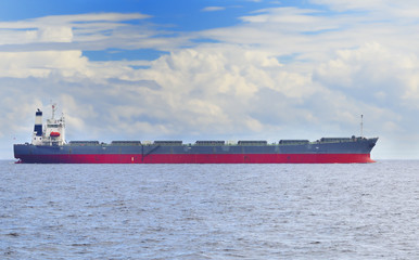 Cargo ship in open sea under cloudy blue sky