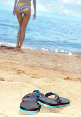 Fototapeta na wymiar Slippers on the beach and woman on a background