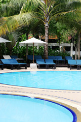 Deck chairs and umbrellas next to a swimming pool.