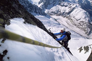 Fotobehang Jonge mannen bergbeklimmen op besneeuwde top © Monkey Business