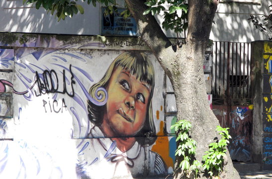 Petite fille tirant la langue derrière un arbre. Brésil.