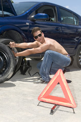 man changing a broken wheel of his car