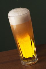 Freshly Poured Beer with Overflowing Foam in a Tall Glass