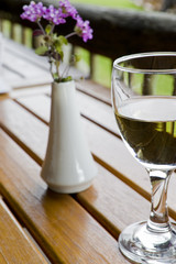 Glass of wine on a wooden table at an outside restaurant.