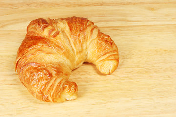 Single croissant on a bread board