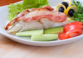 halibut prepared with vegetables and bacon on a plate.close up