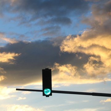 Gr&uuml;nes Verkehrssignal vor dramatischem Himmel