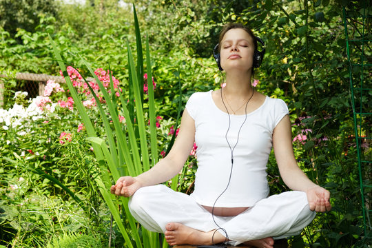 Young Pregnant Woman Listening To A Music At Summer Garden