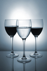 Three glasses with red and white wine on color background