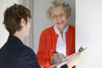 Attractive senior woman signing a document at front door