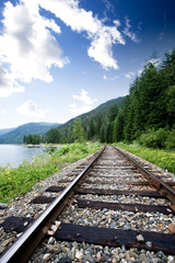 Train tracks near a large lage going through the mountains