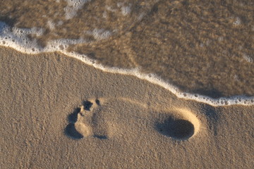 Footprint on beach, wave blurred water to show its movement