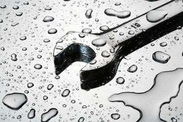 Wrench under a rain with drops on glass