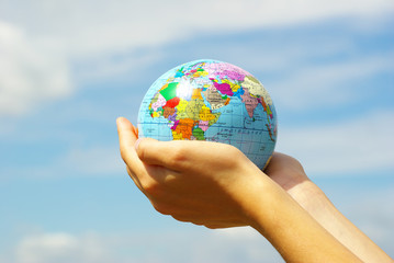 Hand holdings a globe on a sky
