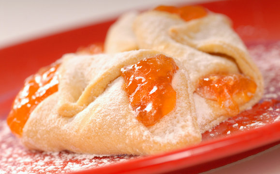 Freshly baked apricot kolache with powdered sugar on a red plate