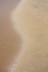 Abstract image of a wave receeding from a sandy beach