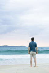 Mann steht am Strand und betrachtet das Meer