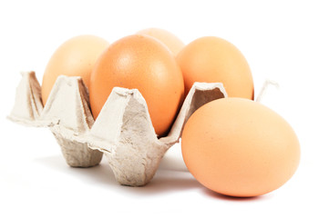 Four eggs lay in cartons cell. Nearby lay another egg.