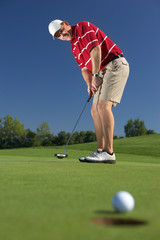 golfball at hole with putting golf player in the back