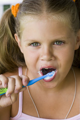 little blond girl cleaning teeth by toothbrush