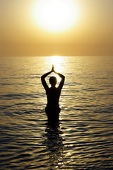 Young beatiful woman meditating in a sea