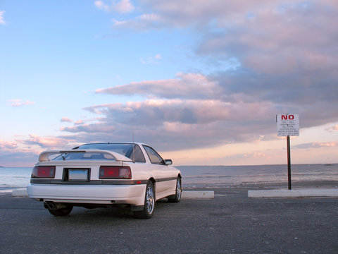 A customized white sports car parked at the beach.