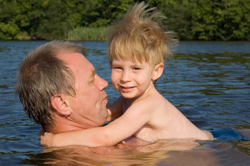 grandfather and grandson swim in the river