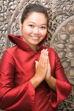 .Young Thai woman in red silk dress greeting.