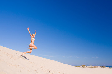 beautiful female exercising on the sand dunes