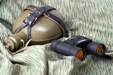 binoculars and bottle on a camouflage background