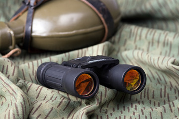 binoculars and bottle on a camouflage background
