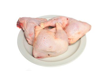 Three raw chicken legs on a white plate