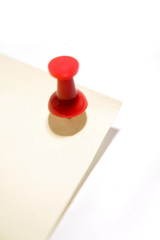Push-pin stuck in corner of yellow note paper